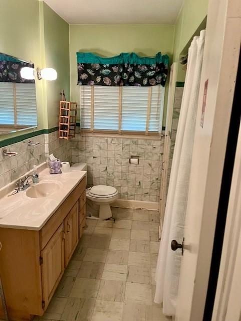 4748 Eastern Ave, Kansas City, MO 64129 - full bathroom with vanity, toilet, tile patterned floors, wainscoting, and tile walls