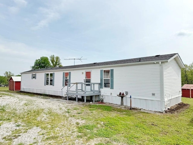 back of property with an outdoor structure, a shed, a deck, and a yard