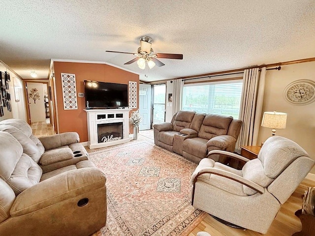 living room with a textured ceiling, crown molding, light wood-style flooring, and a ceiling fan