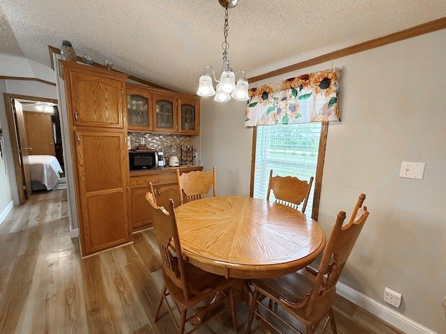 dining room with an inviting chandelier, a textured ceiling, light wood-type flooring, and crown molding