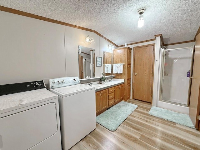 bathroom featuring a shower stall, separate washer and dryer, crown molding, a textured ceiling, and wood finished floors