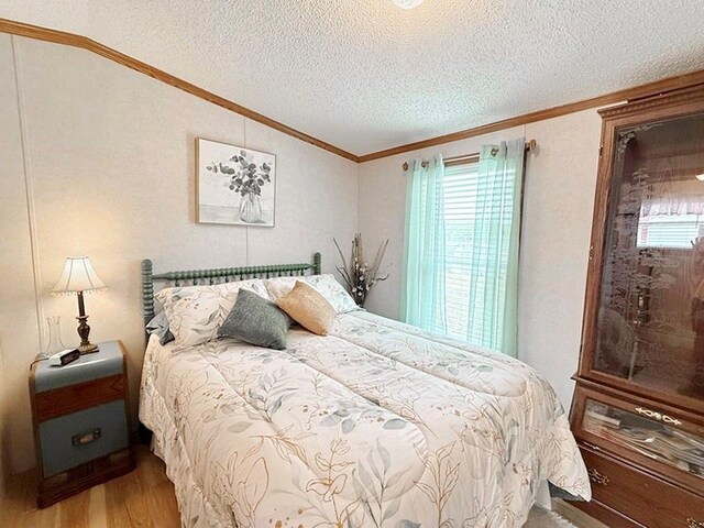 bedroom featuring crown molding, lofted ceiling, wood finished floors, and a textured ceiling