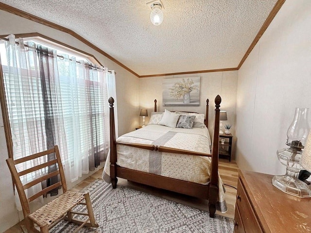 bedroom with a textured ceiling, crown molding, light wood finished floors, and vaulted ceiling