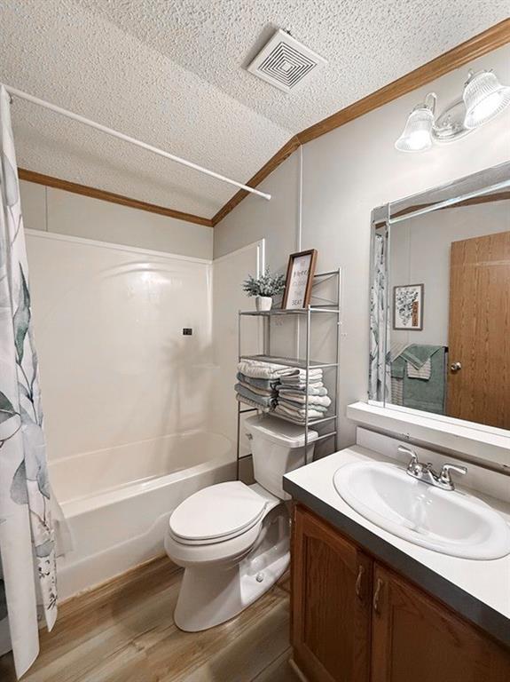 bathroom featuring shower / bath combo, a textured ceiling, crown molding, visible vents, and wood finished floors