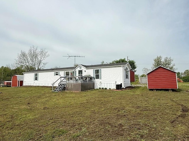 back of house with a deck, an outdoor structure, a yard, a storage unit, and cooling unit