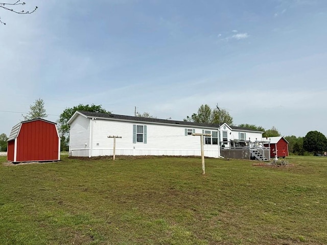 back of house featuring a lawn, an outdoor structure, and a storage unit