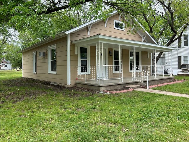 bungalow with a porch, a front lawn, and cooling unit