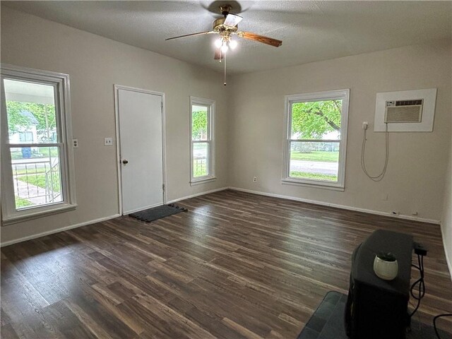 entrance foyer with ceiling fan, a wall unit AC, dark wood finished floors, and baseboards