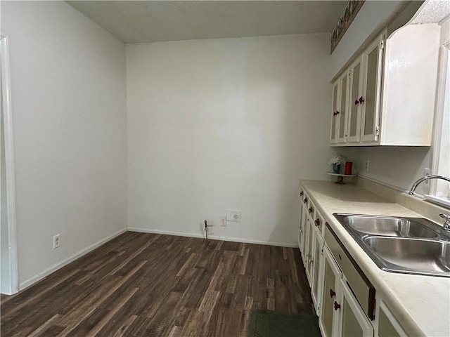 kitchen featuring a sink, white cabinets, dark wood-style flooring, and light countertops