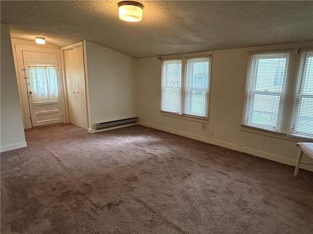 carpeted empty room featuring a baseboard heating unit, a textured ceiling, a wealth of natural light, and baseboards