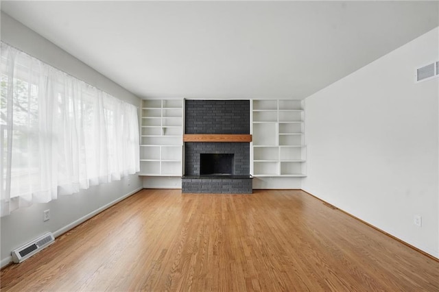 unfurnished living room with baseboards, a fireplace, wood finished floors, and visible vents