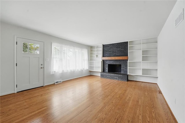 unfurnished living room featuring baseboards, visible vents, wood finished floors, and a fireplace