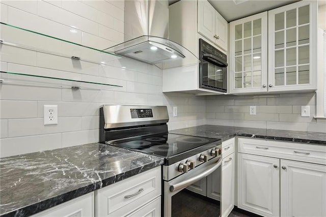 kitchen with glass insert cabinets, tasteful backsplash, wall chimney exhaust hood, and stainless steel range with electric stovetop