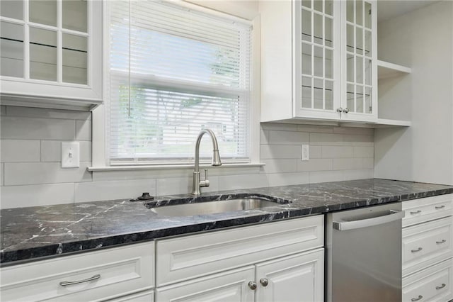 kitchen with glass insert cabinets, white cabinetry, tasteful backsplash, a sink, and dishwasher