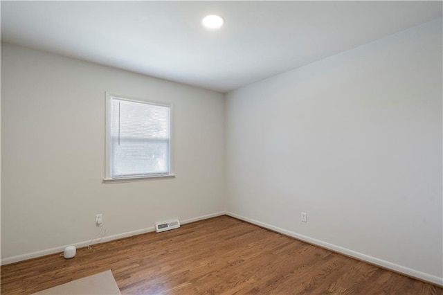 empty room with baseboards, wood finished floors, and visible vents