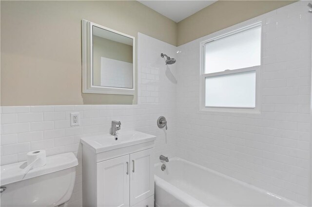 full bath featuring tile walls, wainscoting, vanity, toilet, and shower / bathtub combination
