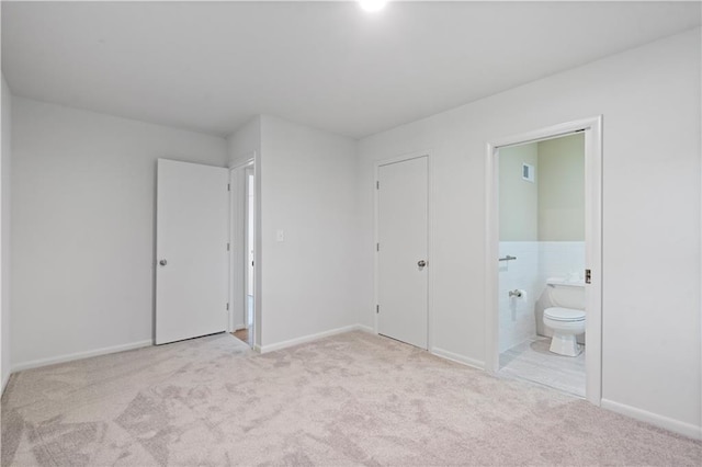 unfurnished bedroom with baseboards, visible vents, carpet, and ensuite bath