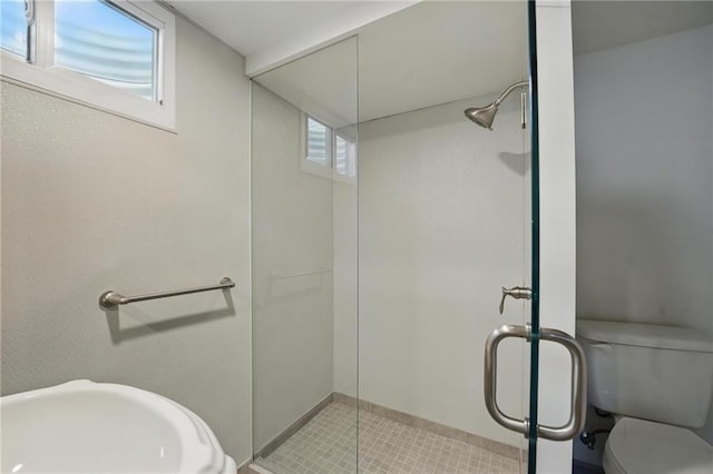 bathroom with toilet, a sink, tile patterned flooring, and a stall shower