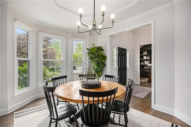 dining space with baseboards, a chandelier, dark wood-type flooring, crown molding, and a tray ceiling