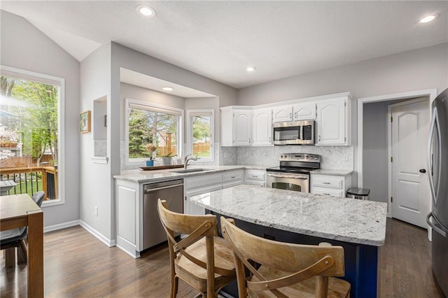 kitchen featuring stainless steel appliances, a sink, decorative backsplash, white cabinets, and plenty of natural light
