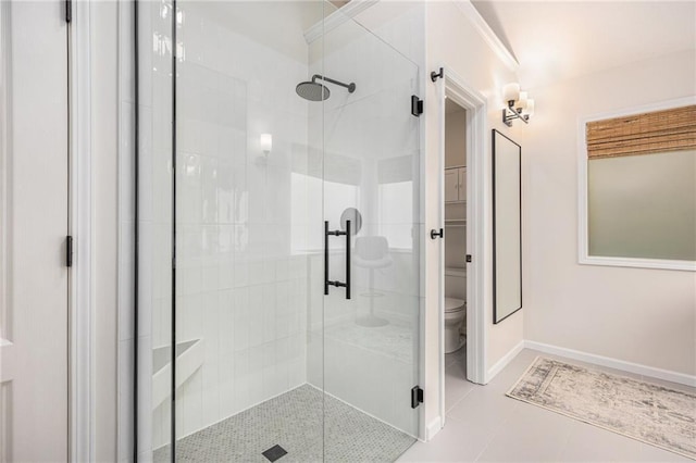 full bath featuring a stall shower, toilet, tile patterned flooring, and baseboards