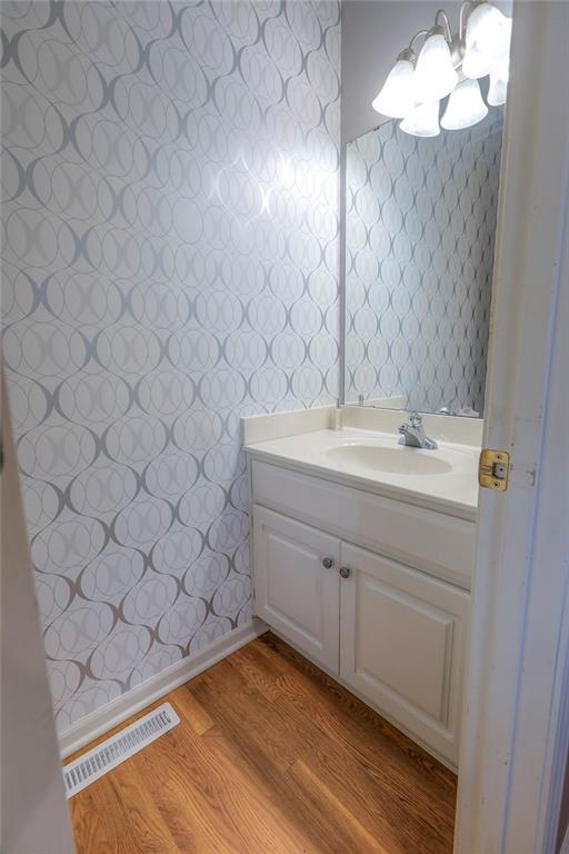 812 SW Stablewood Cir, Lees Summit, MO 64081 - bathroom featuring wallpapered walls, vanity, wood finished floors, and a chandelier