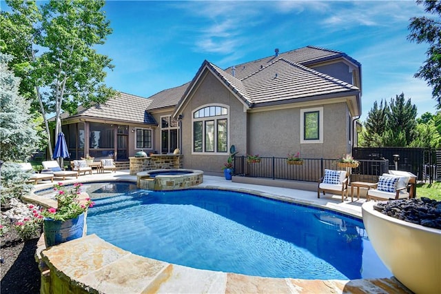 view of swimming pool featuring a patio area, fence, a pool with connected hot tub, and a sunroom