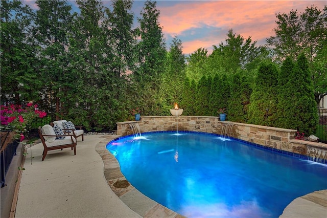 pool at dusk featuring a patio area