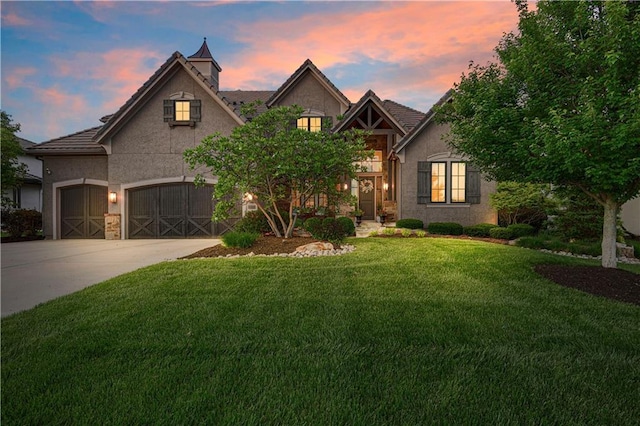 view of front of home with stucco siding, a yard, concrete driveway, a tile roof, and a garage