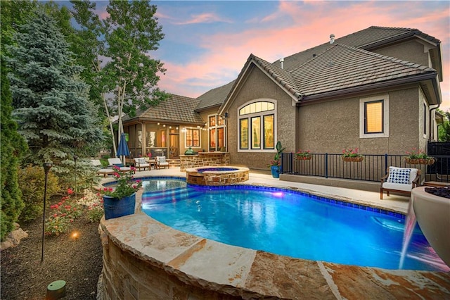 16305 Flint St, Overland Park, KS 66221 - pool at dusk featuring a patio area and a pool with connected hot tub