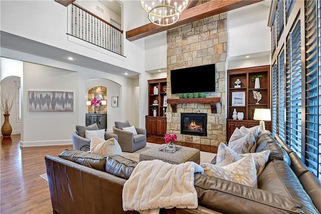 16305 Flint St, Overland Park, KS 66221 - living room featuring a fireplace, arched walkways, wood finished floors, a towering ceiling, and a chandelier