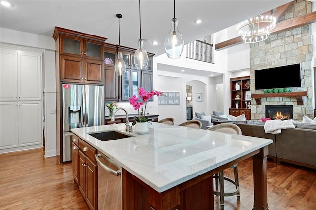 16305 Flint St, Overland Park, KS 66221 - kitchen with a sink, stainless steel appliances, light wood-style floors, arched walkways, and a center island with sink