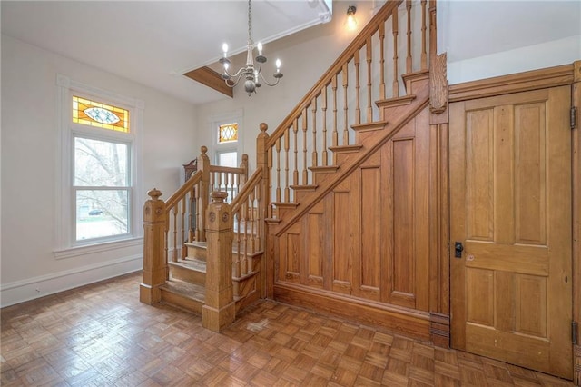 stairway featuring a chandelier and baseboards