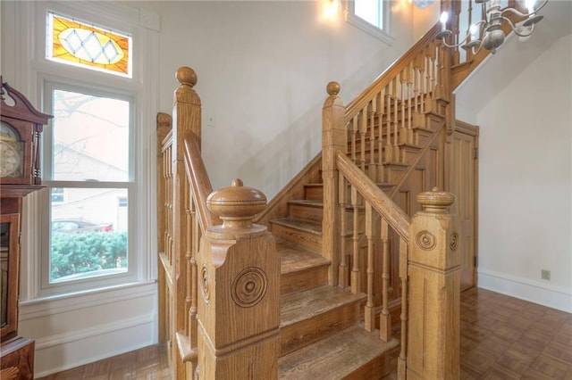 stairway with a chandelier, plenty of natural light, and baseboards