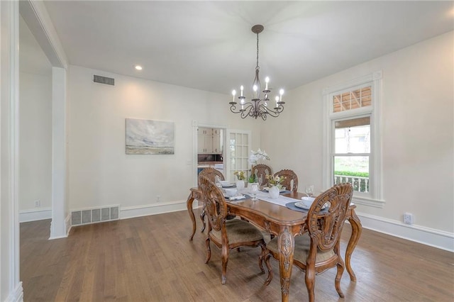 dining space featuring visible vents, wood finished floors, a chandelier, and baseboards