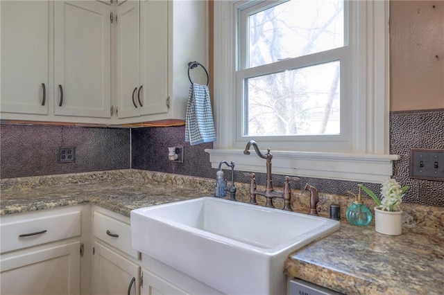 kitchen featuring a sink, white cabinets, and decorative backsplash