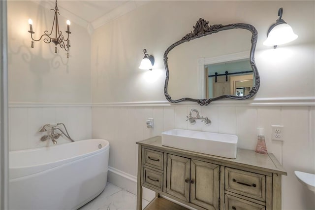 bathroom featuring a soaking tub, vanity, marble finish floor, and wainscoting