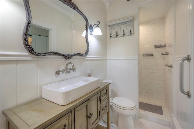 full bath featuring a decorative wall, toilet, a wainscoted wall, and tiled shower