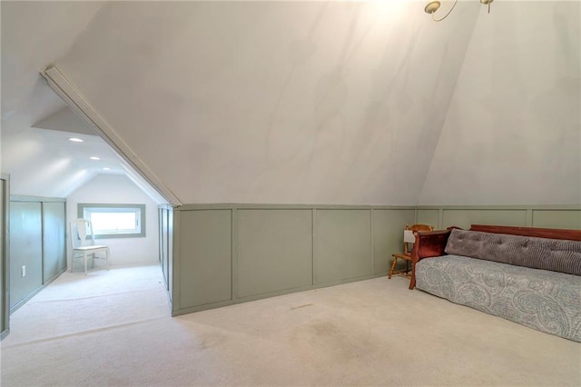 carpeted bedroom with connected bathroom, a decorative wall, and vaulted ceiling
