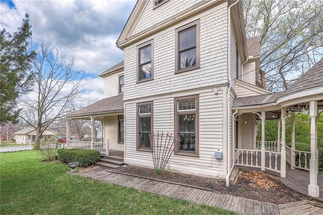view of front of home featuring covered porch, a shingled roof, and a front lawn