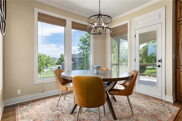 dining space with a chandelier, wood finished floors, healthy amount of natural light, and ornamental molding