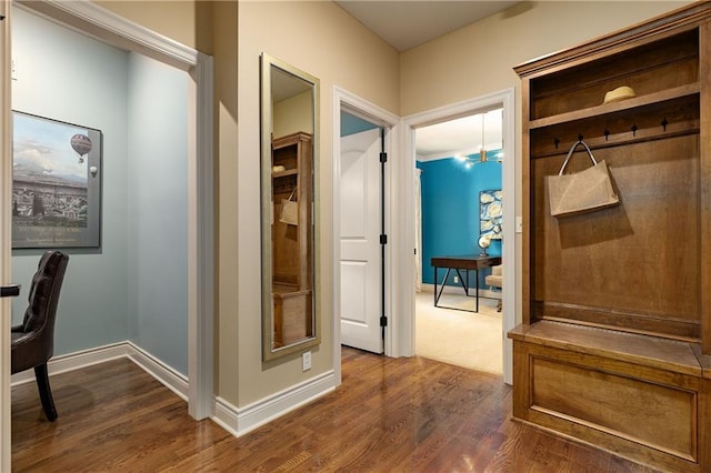 hall with dark wood-type flooring, baseboards, and a desk