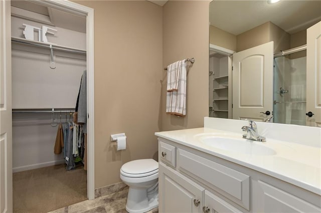bathroom featuring a stall shower, toilet, vanity, and a walk in closet