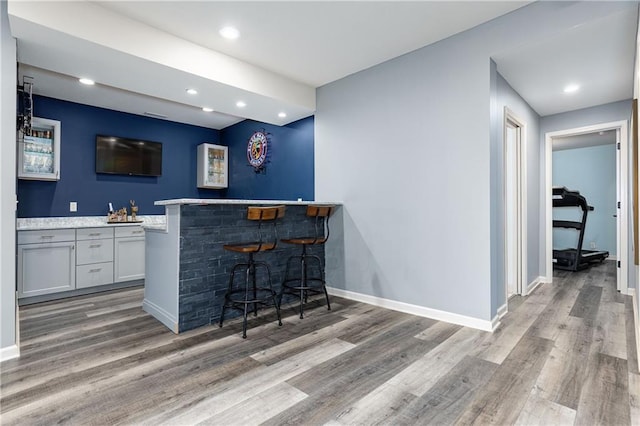 indoor dry bar with wood finished floors, recessed lighting, and baseboards