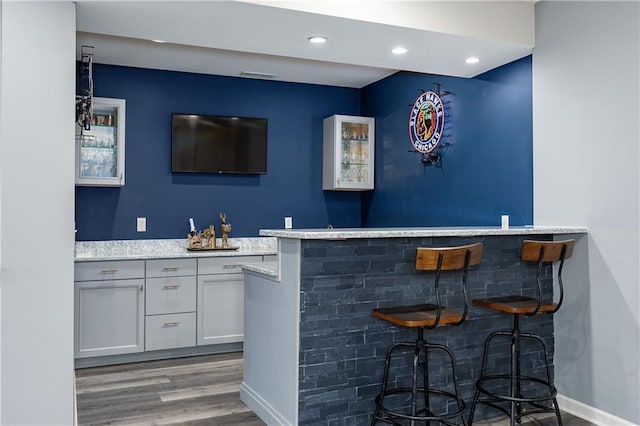 indoor wet bar featuring wood finished floors and recessed lighting