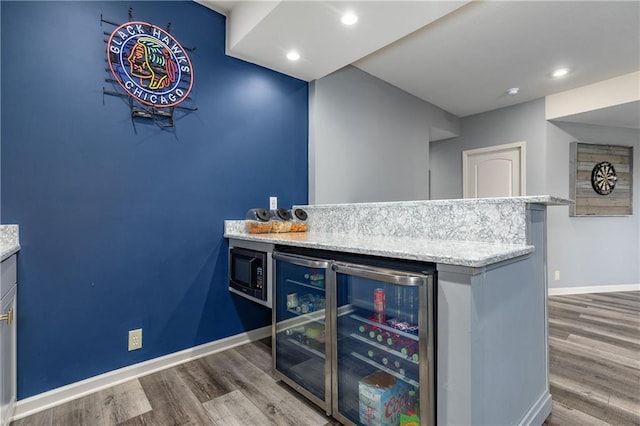indoor dry bar featuring wood finished floors, beverage cooler, built in microwave, baseboards, and recessed lighting