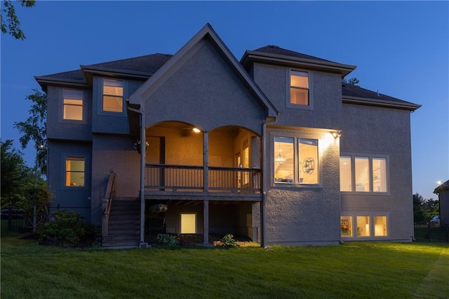 rear view of property with a yard, stucco siding, and stairs