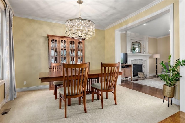 10804 W 169th St, Overland Park, KS 66221 - dining space featuring a fireplace, a chandelier, baseboards, wood finished floors, and crown molding