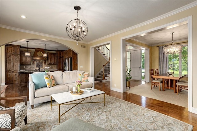 10804 W 169th St, Overland Park, KS 66221 - living area with arched walkways, a chandelier, wood finished floors, crown molding, and stairway