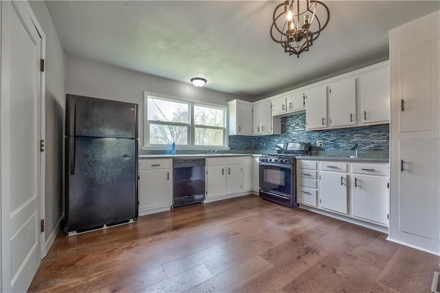 kitchen featuring white cabinetry, tasteful backsplash, a sink, black appliances, and dark wood-style flooring